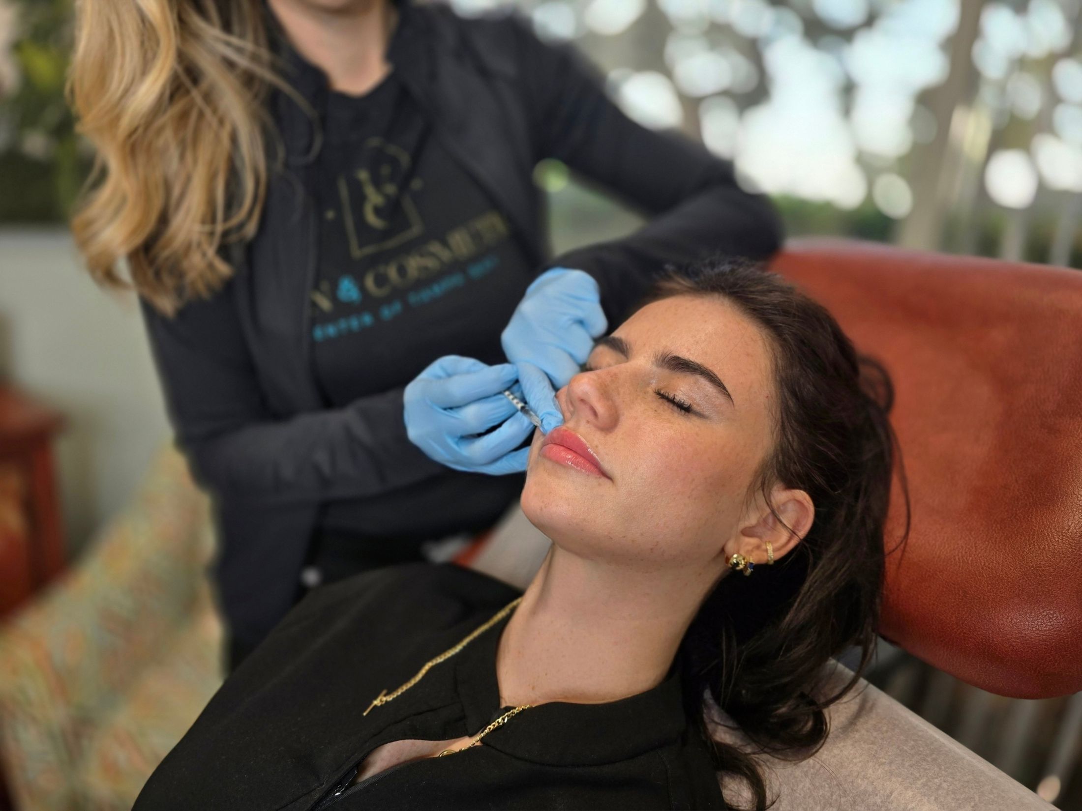 Woman receiving cosmetic injectable treatment on face.