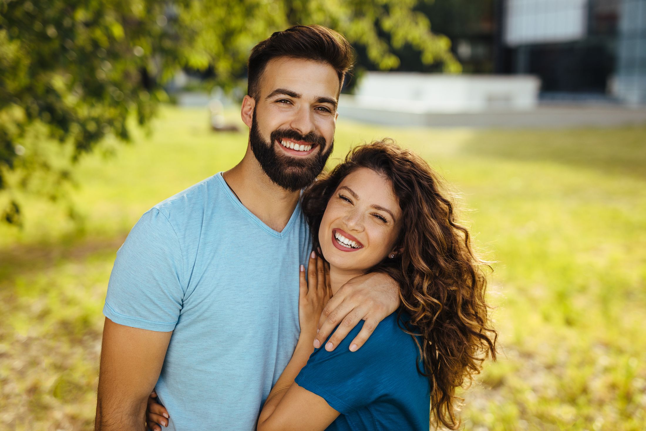 Happy couple smiling outdoors in bright sunlight.