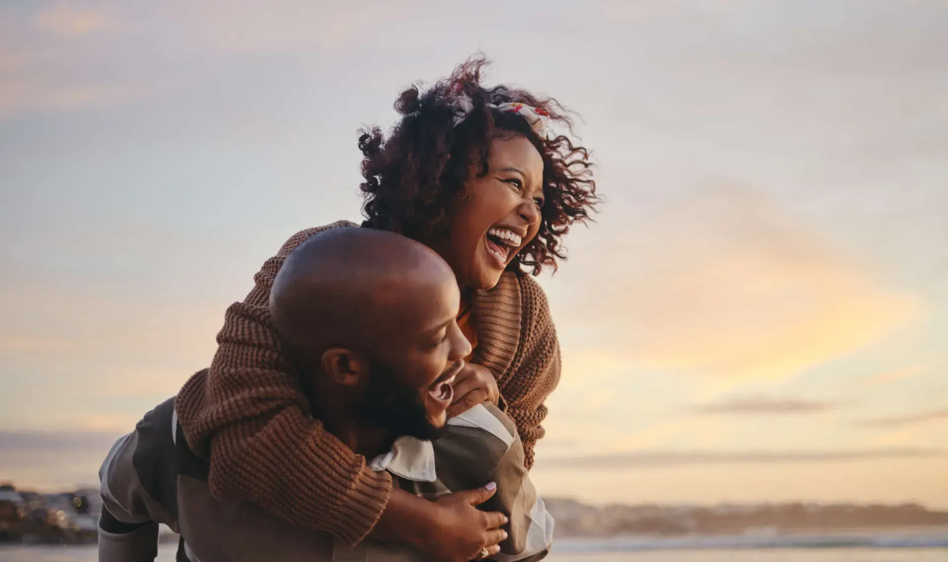 Joyful couple embracing at sunset outdoors.