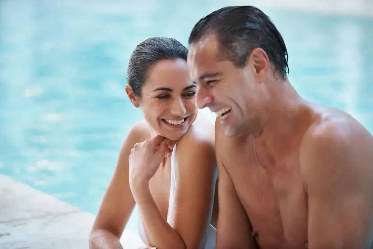 Couple laughing together by the pool.