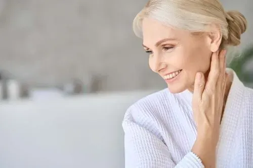 Smiling woman touching her neck, relaxing at home.