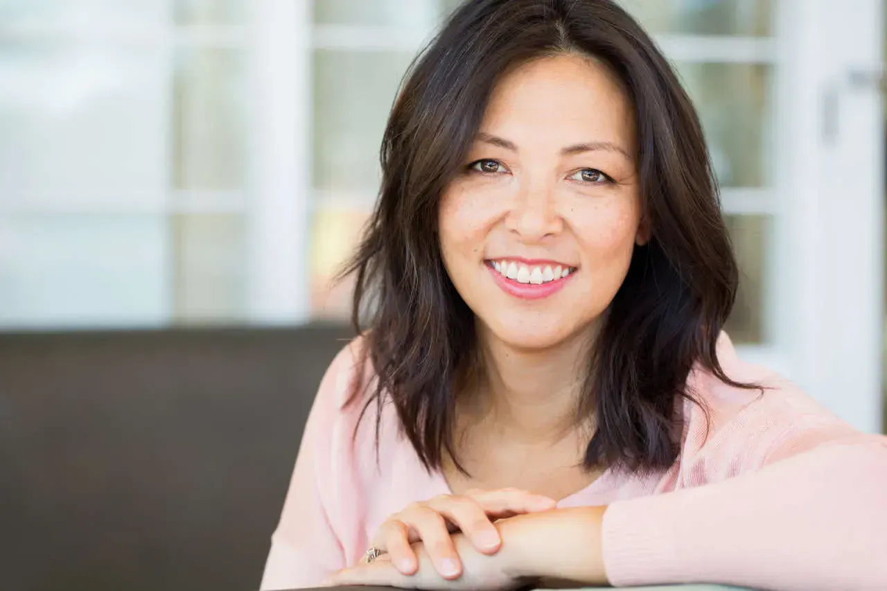 Smiling woman in a cozy indoor setting.