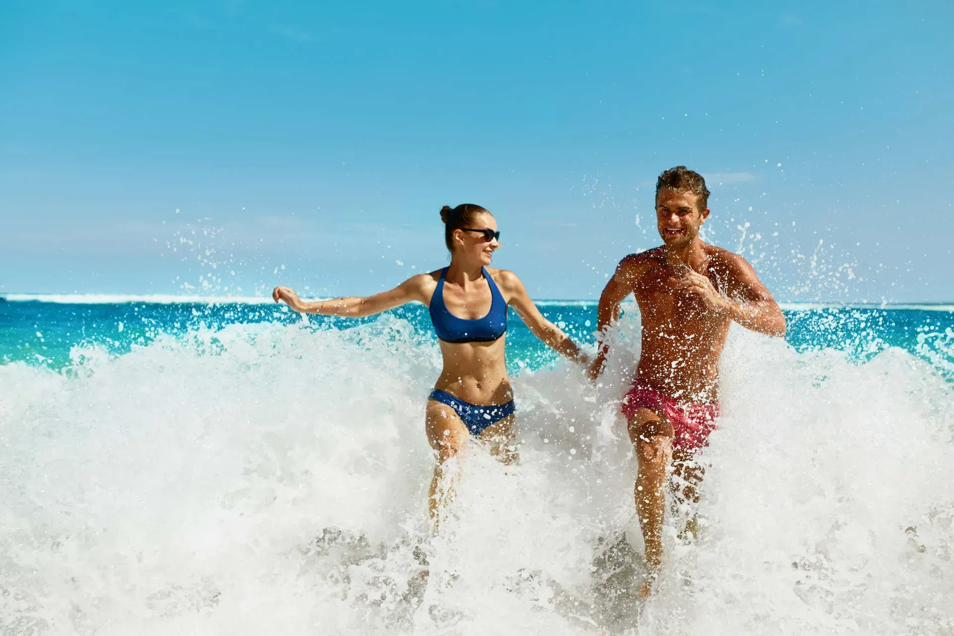 Couple playing in ocean waves on beach.